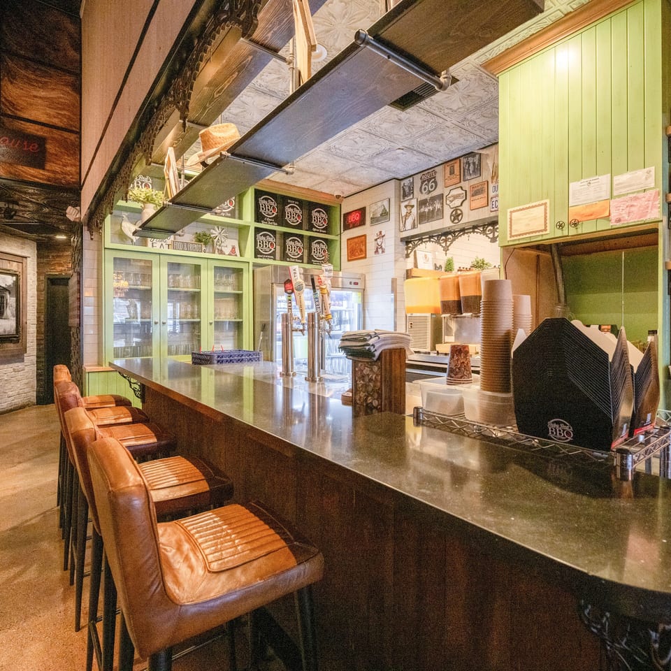 Rustic Ruby Red’s BBQ restaurant bar with leather stools, beer taps, green cabinetry, and vintage Route 66 decor.